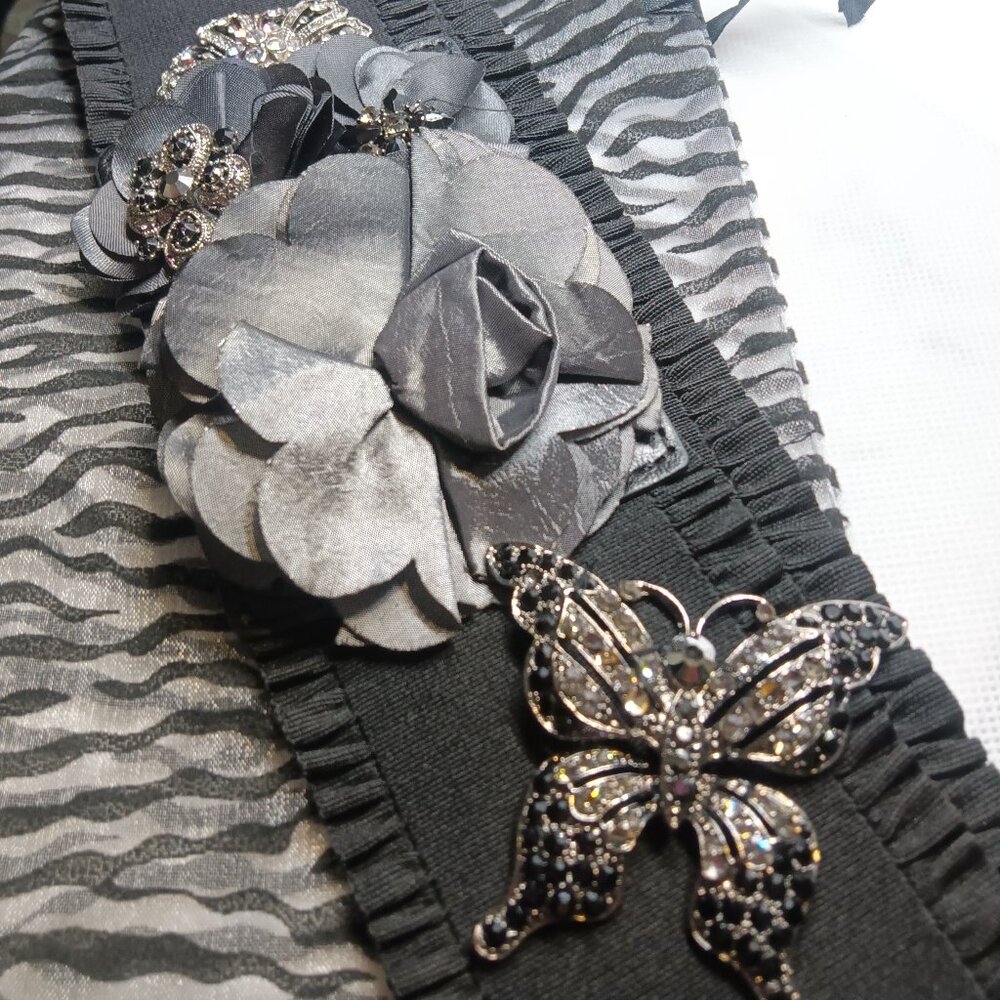 A handmade black stretch belt embellished with shimmery flowers and brooches
